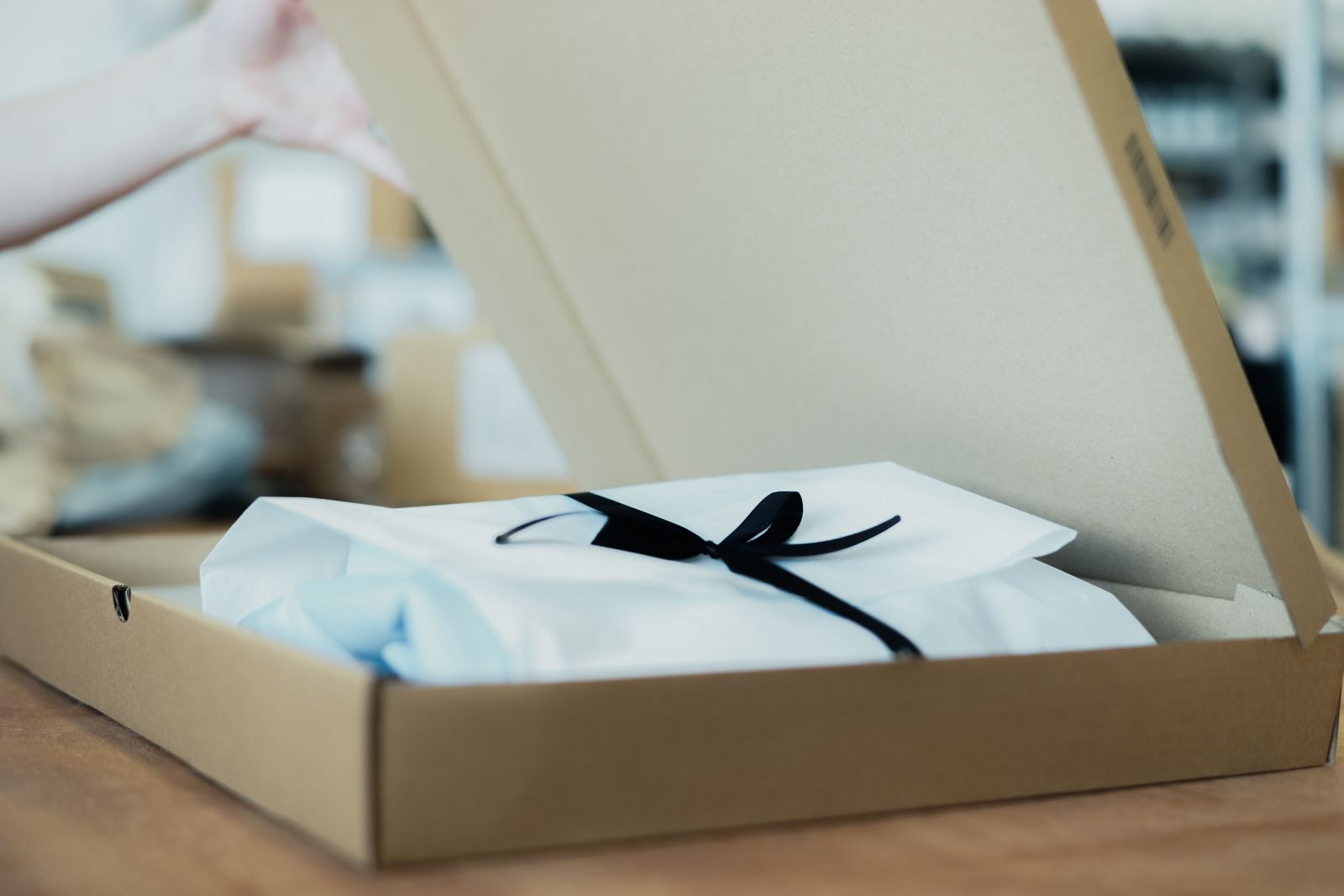 Apparel wrapped in tissue paper with a ribbon in a kraft box